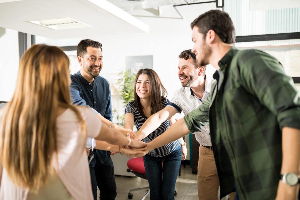 Equipe de salariés souriants qui ont les mains posées les unes sur les autres