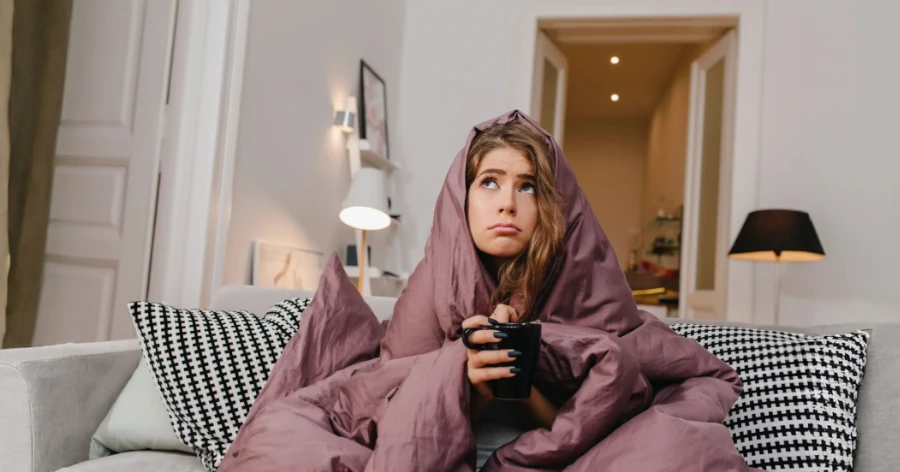 Femme installée sous sa couette regardant le plafond, visiblement dérangée par le bruit au dessus